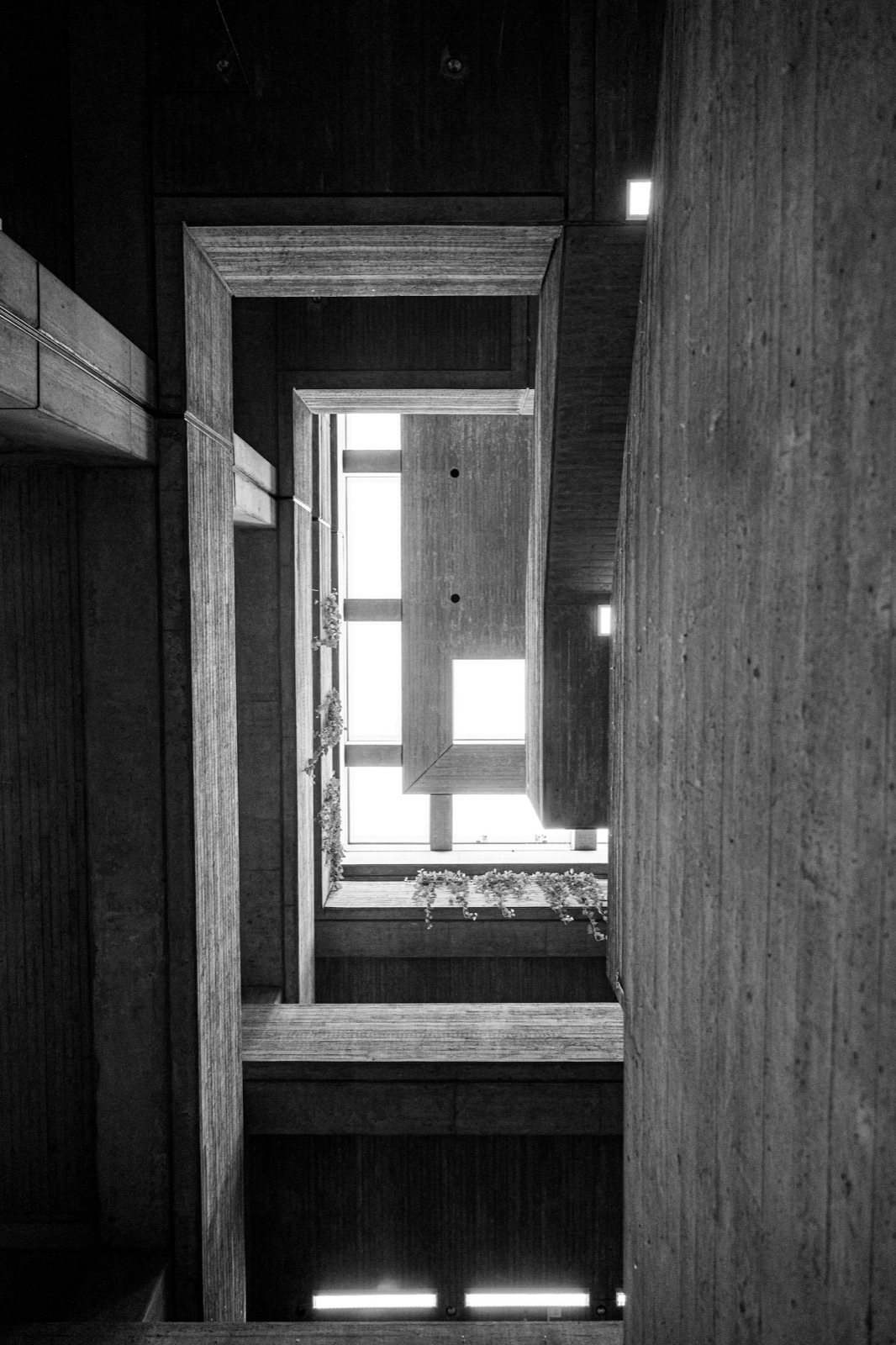Concrete atrium in black and white, looking up through nested frames toward a skylight